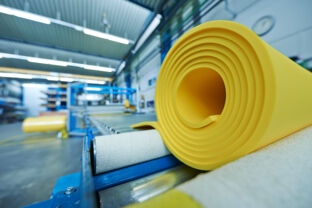 Rollers made of yellow polyurethane elastomer on a conveyor belt in a production hall.