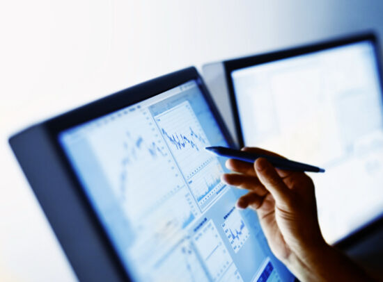 A hand uses a stylus to tap on a computer monitor displaying a vibration analysis graph. A hand uses a stylus to tap on a computer monitor displaying a vibration analysis graph.