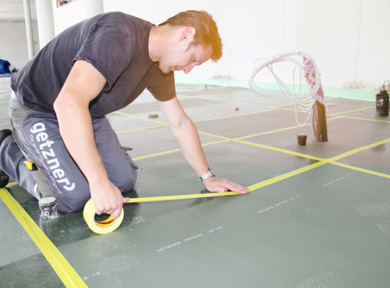 Getzner Werkstoffe worker installing mats made of cellular elastomer for floor vibration isolation. Getzner Werkstoffe worker installing mats made of cellular elastomer for floor vibration isolation.
