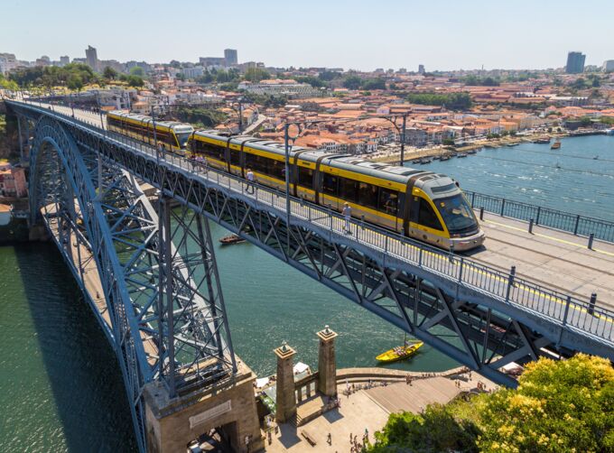 Yellow underground train on a steel arch bridge over a river, with the city in the background. Yellow underground train on a steel arch bridge over a river, with the city in the background.