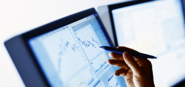 A hand uses a stylus to tap on a computer monitor displaying a vibration analysis graph. A hand uses a stylus to tap on a computer monitor displaying a vibration analysis graph.