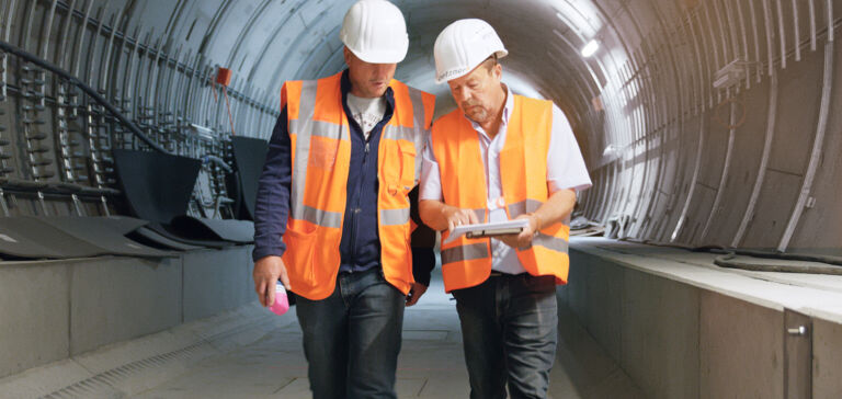 Two construction workers performing a vibration analysis in a railway tunnel. Two construction workers performing a vibration analysis in a railway tunnel.
