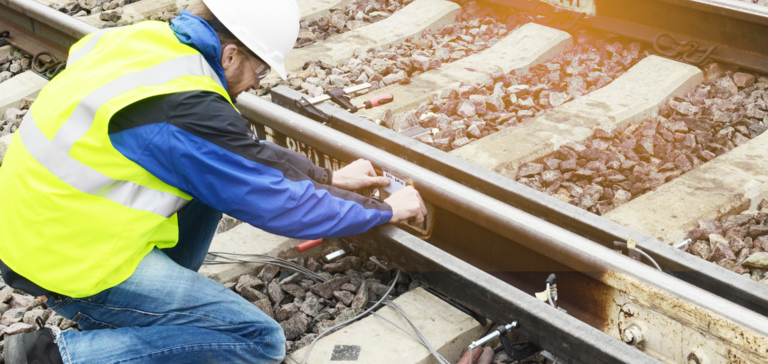 Worker installing measuring devices for vibration analysis on railway tracks. Worker installing measuring devices for vibration analysis on railway tracks.