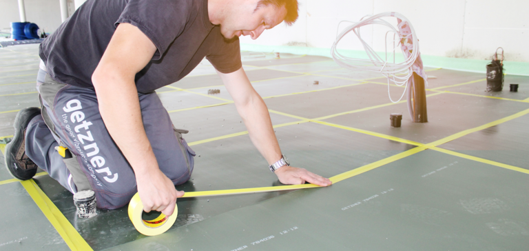 Getzner Werkstoffe worker installing mats made of cellular elastomer for floor vibration isolation. Getzner Werkstoffe worker installing mats made of cellular elastomer for floor vibration isolation.
