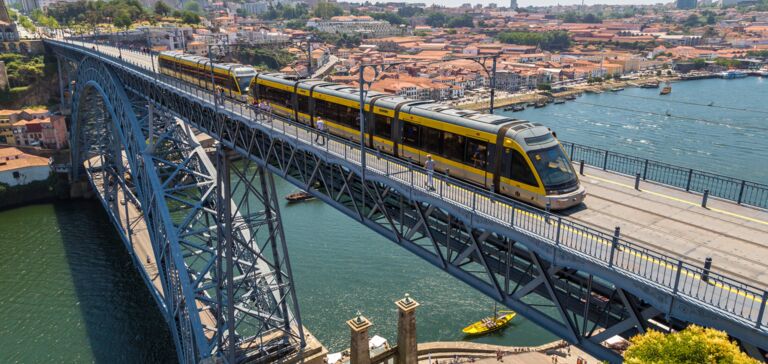 Yellow underground train on a steel arch bridge over a river, with the city in the background. Yellow underground train on a steel arch bridge over a river, with the city in the background.