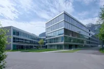 Modern Getzner Werkstoffe building in Bürs: glass facades, meadows, mountains.